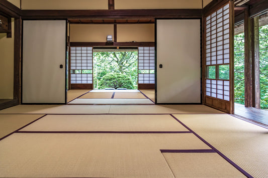 Traditional Japanese room with tatami mats, sliding shoji doors, and a serene view of nature.