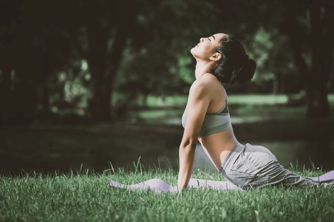 Yoga practitioner performing an upward-facing pose on a yoga mat in a peaceful outdoor setting.