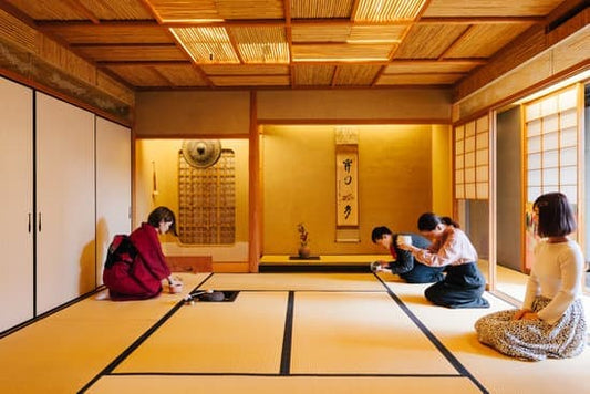 Traditional Japanese tea ceremony taking place in a tatami room, with participants seated gracefully on the tatami mats.